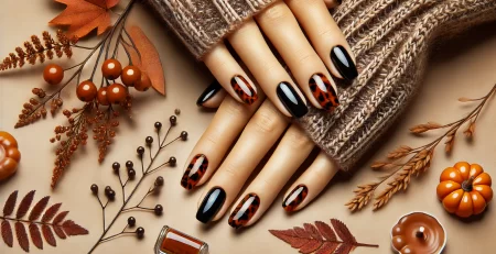 Stylish hands with tortoise shell manicure in warm, autumn tones, set against a cozy fall-themed background.